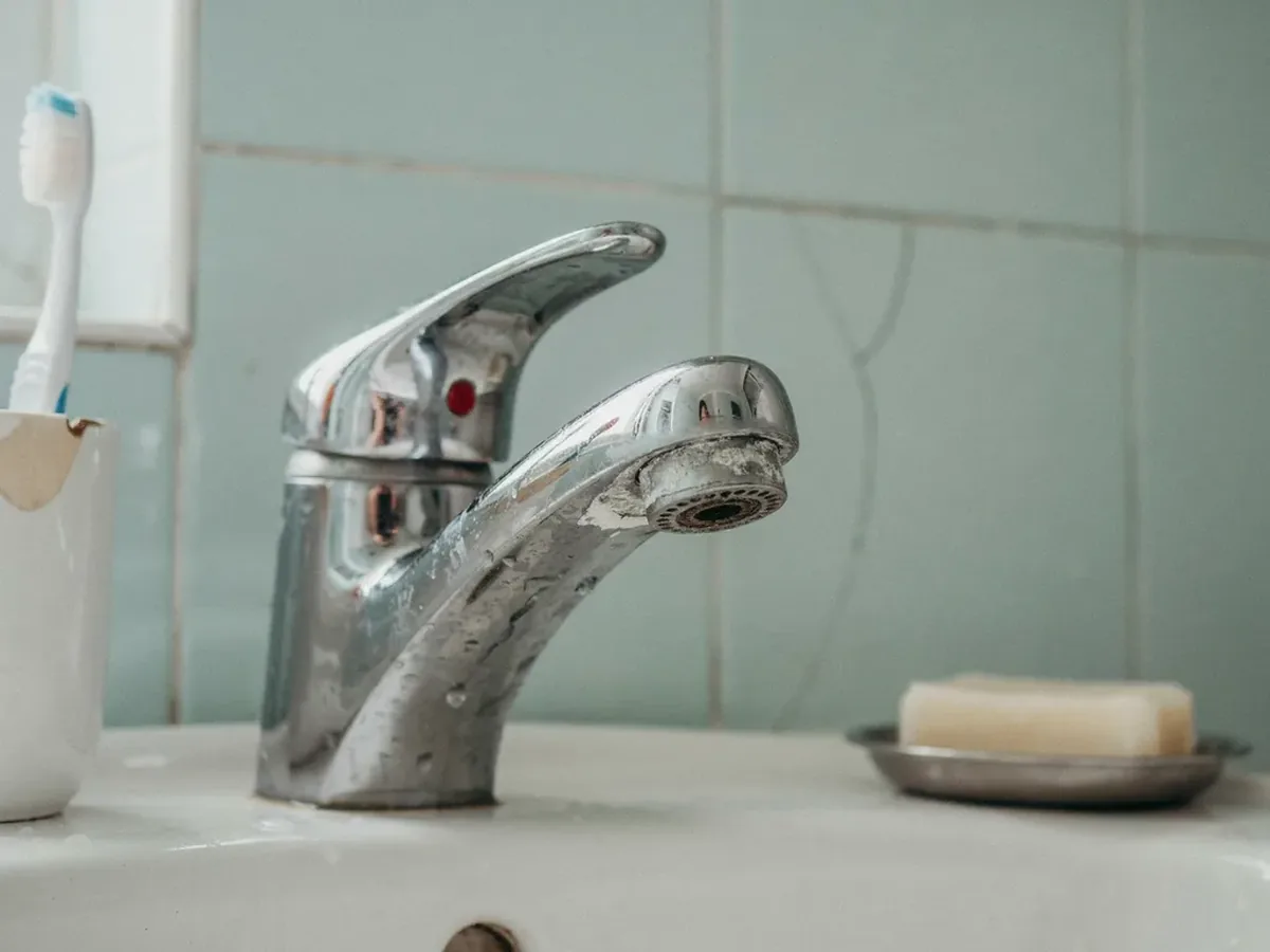 Bathroom faucet and aerator crusted with thick white limescale from hard water