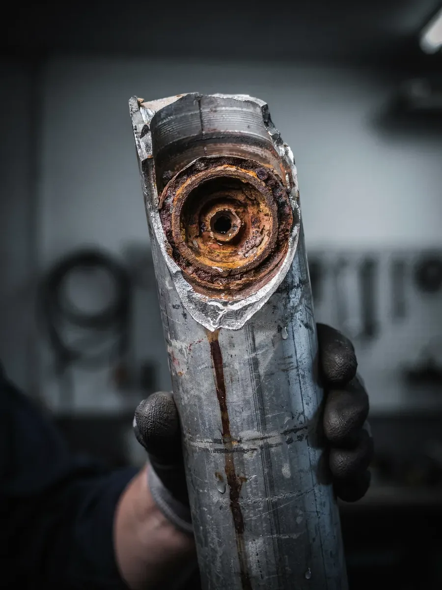 Cut section of old galvanized steel water pipe, the inside choked with rust and mineral scale down to a small opening