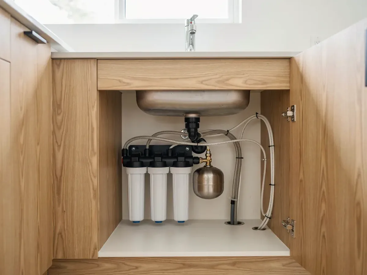 Under-sink reverse osmosis system with filter canisters and a storage tank installed inside a kitchen cabinet
